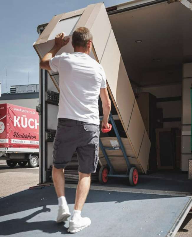 Tragen von Möbeln beim Umzug – erfahrenes Umzugsunternehmen Ulm beim Beladen des Transporters
